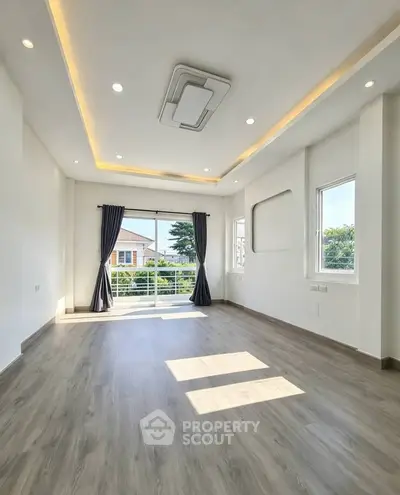 Spacious modern living room with large windows and balcony access, featuring elegant ceiling design.