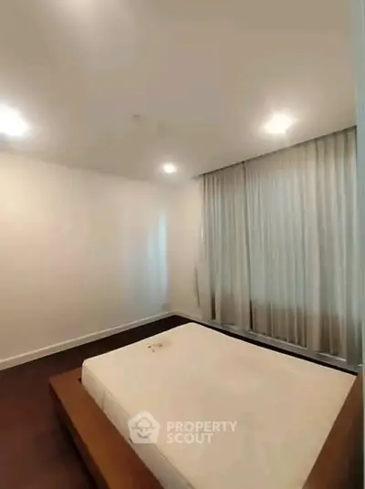 Spacious bedroom with large windows and modern lighting, perfect for relaxation.