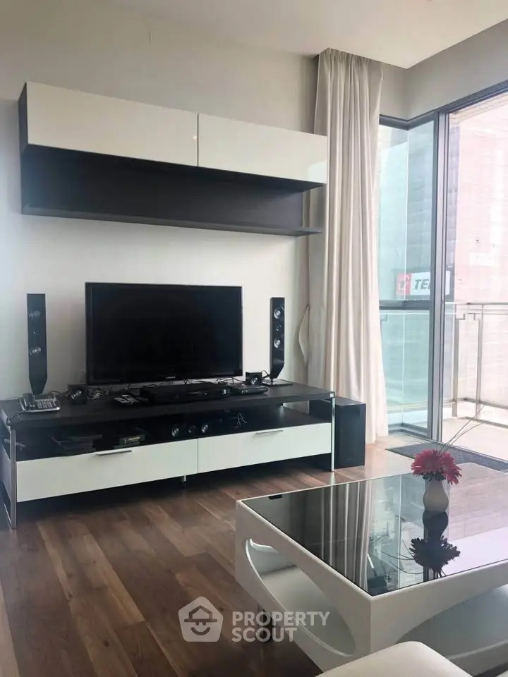 Modern living room with sleek furniture and large glass doors leading to a balcony.