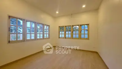 Spacious empty room with large windows and wooden flooring, perfect for customization.