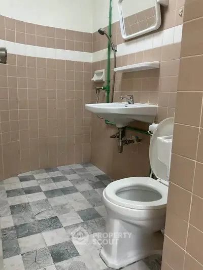 Compact bathroom with tiled walls and floor, featuring a toilet and sink.