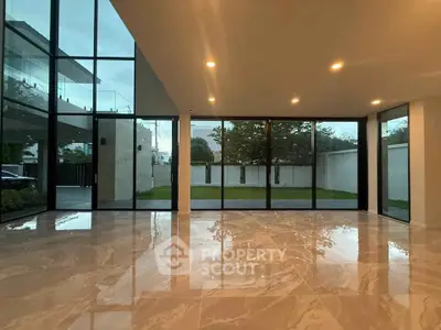 Spacious modern living room with floor-to-ceiling windows and polished marble floors.