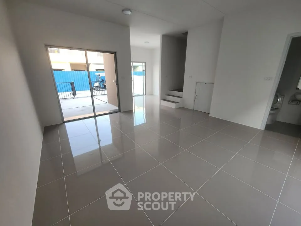 Spacious modern living room with glossy tiled floors and sliding glass doors