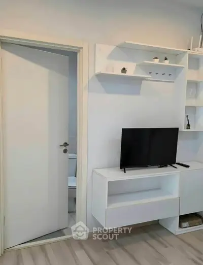 Modern living room with sleek white shelves and TV unit, showcasing minimalist design and functionality.