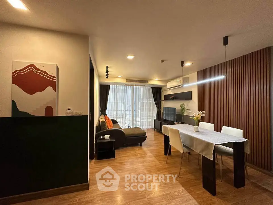 Modern living room with stylish decor and dining area, featuring wood flooring and ambient lighting.