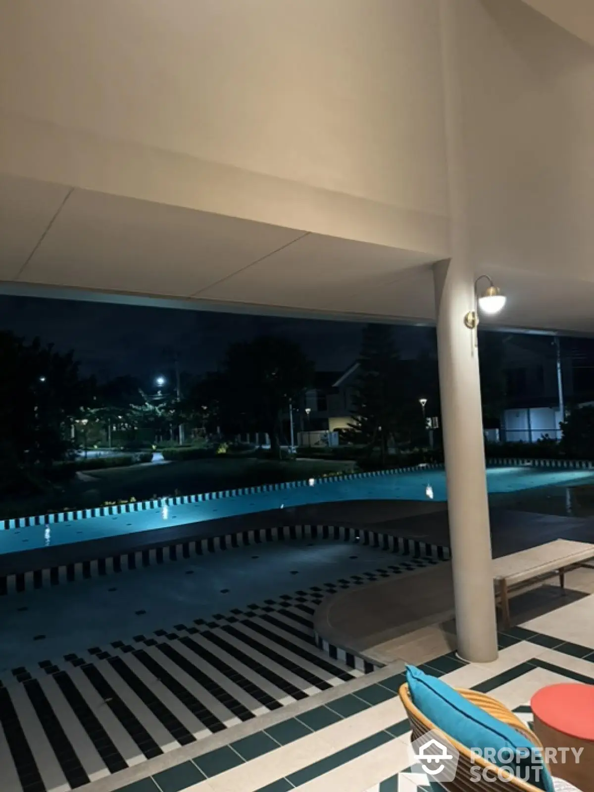 Luxurious poolside view at night with stylish outdoor seating and ambient lighting.