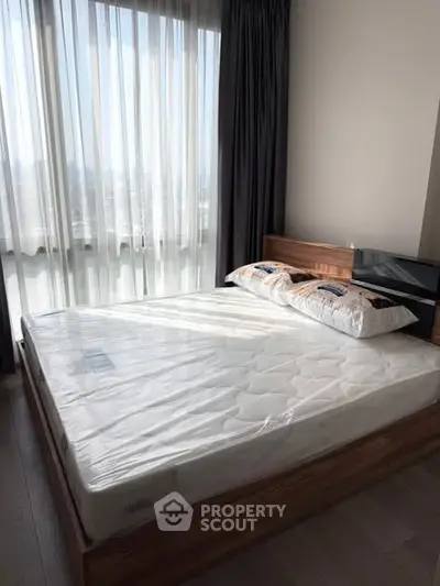 Modern bedroom with large window and natural light in a stylish apartment.