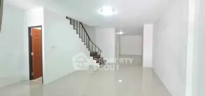Spacious empty living room with staircase and glossy white flooring in modern home.