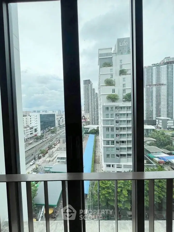 Stunning cityscape view from a modern balcony with high-rise buildings and lush greenery.
