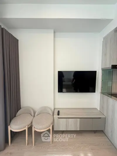 Modern living room with wall-mounted TV and stylish furniture in a contemporary apartment.