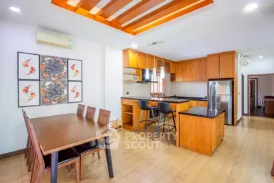 Spacious modern kitchen with wooden cabinets and dining area, featuring stylish lighting and open layout.