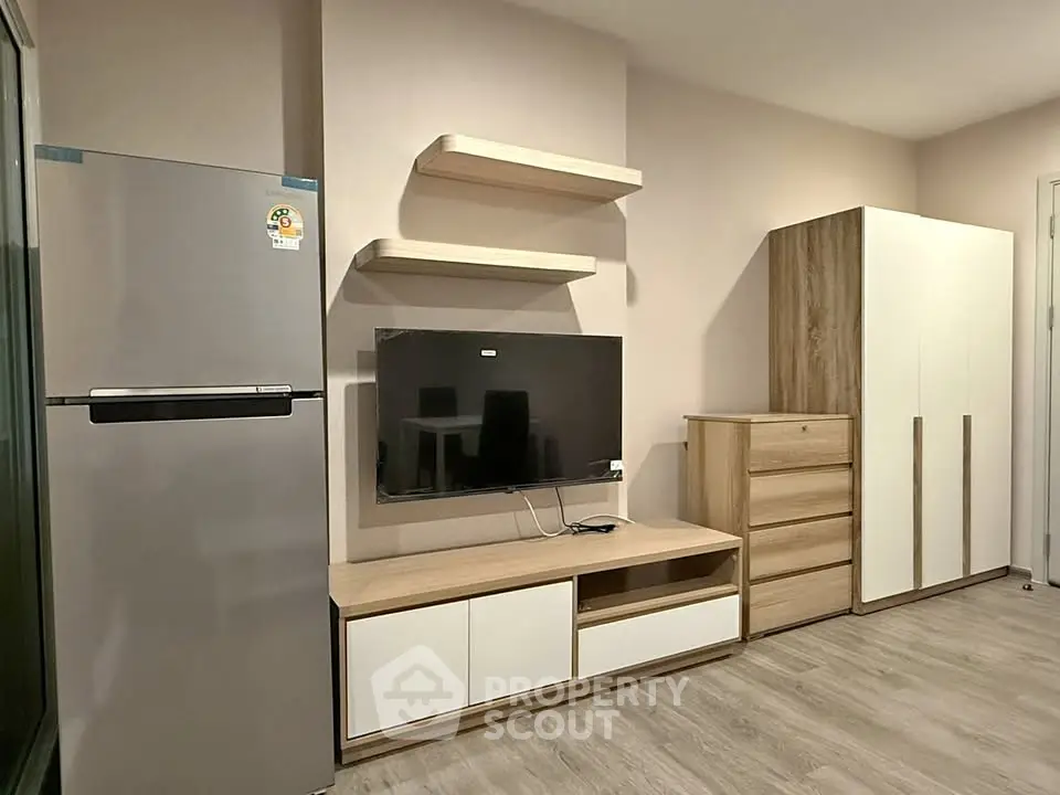Modern living room with sleek furniture and stainless steel fridge, perfect for contemporary living.