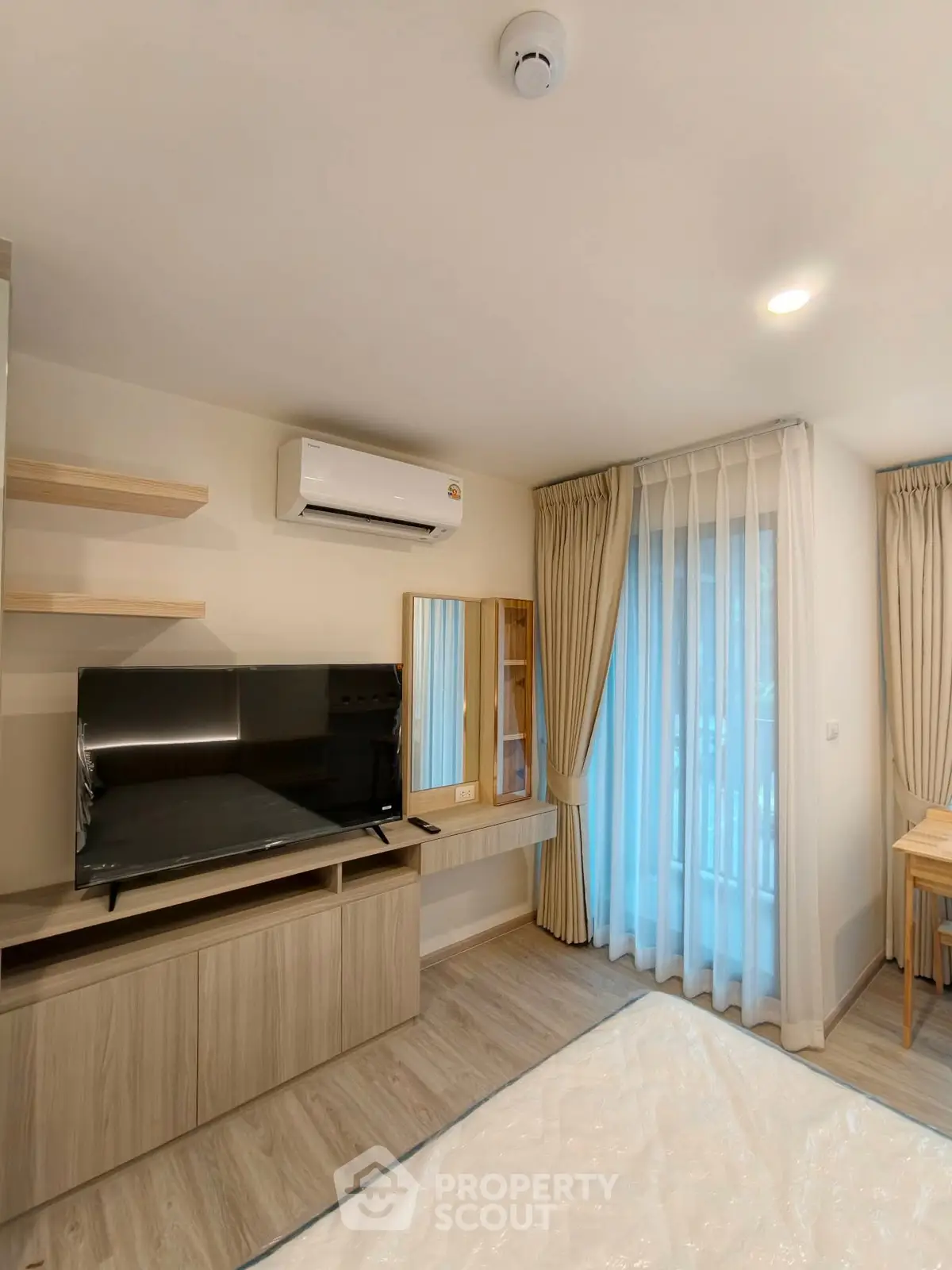 Modern living room with TV, air conditioning, and elegant curtains in a cozy apartment.