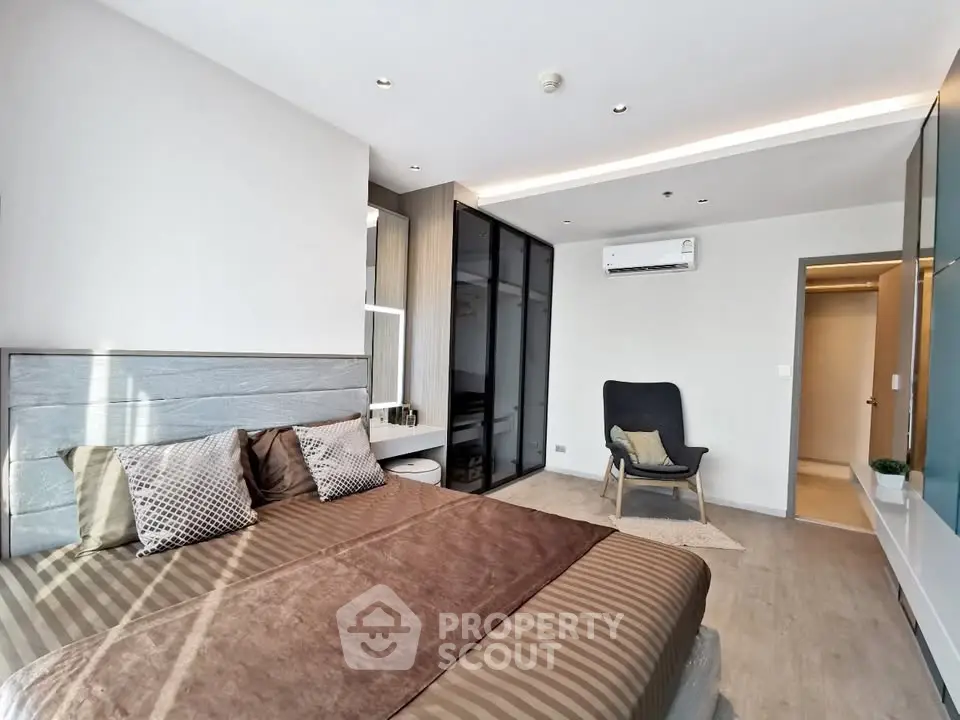 Modern bedroom with stylish decor and ample natural light, featuring a cozy bed and sleek furnishings.