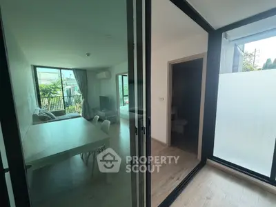 Modern living room with large windows and dining area, featuring sleek design and natural light.