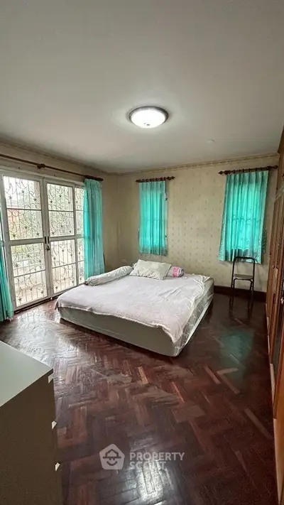 Spacious bedroom with large windows and wooden flooring for natural ambiance.