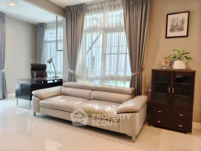 Modern living room with sleek leather sofa and elegant office desk, perfect for stylish home office setup.