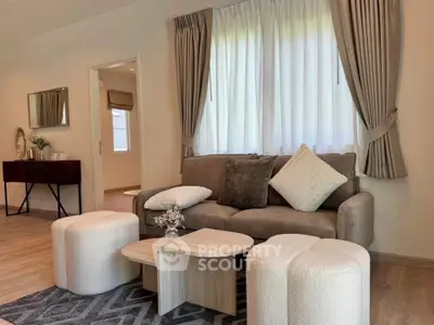 Elegant living room with cozy sofa, stylish coffee table, and plush ottomans, perfect for relaxation.