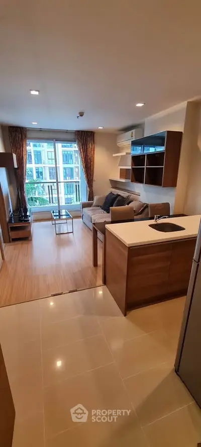 Modern open-plan living room with kitchen, featuring stylish furniture and large windows with city view.