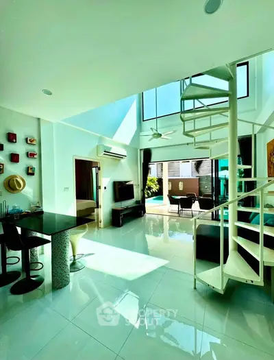 Stunning open-plan living room with spiral staircase and abundant natural light