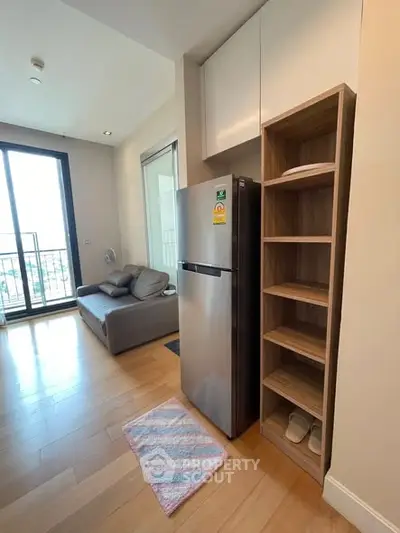 Modern apartment with open layout, featuring a sleek kitchen and cozy living area with balcony access.