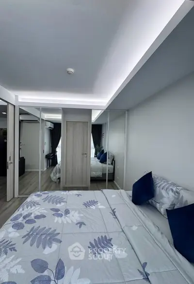 Modern bedroom with mirrored closet doors and stylish bedding in a contemporary apartment.