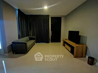 Modern living room with sleek furniture and minimalist design, featuring a comfortable sofa and a flat-screen TV.