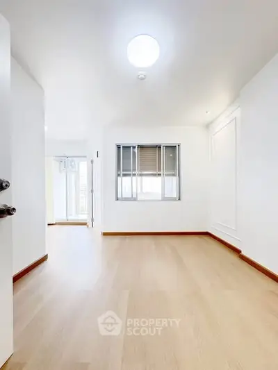 Spacious empty room with wooden flooring and bright natural light