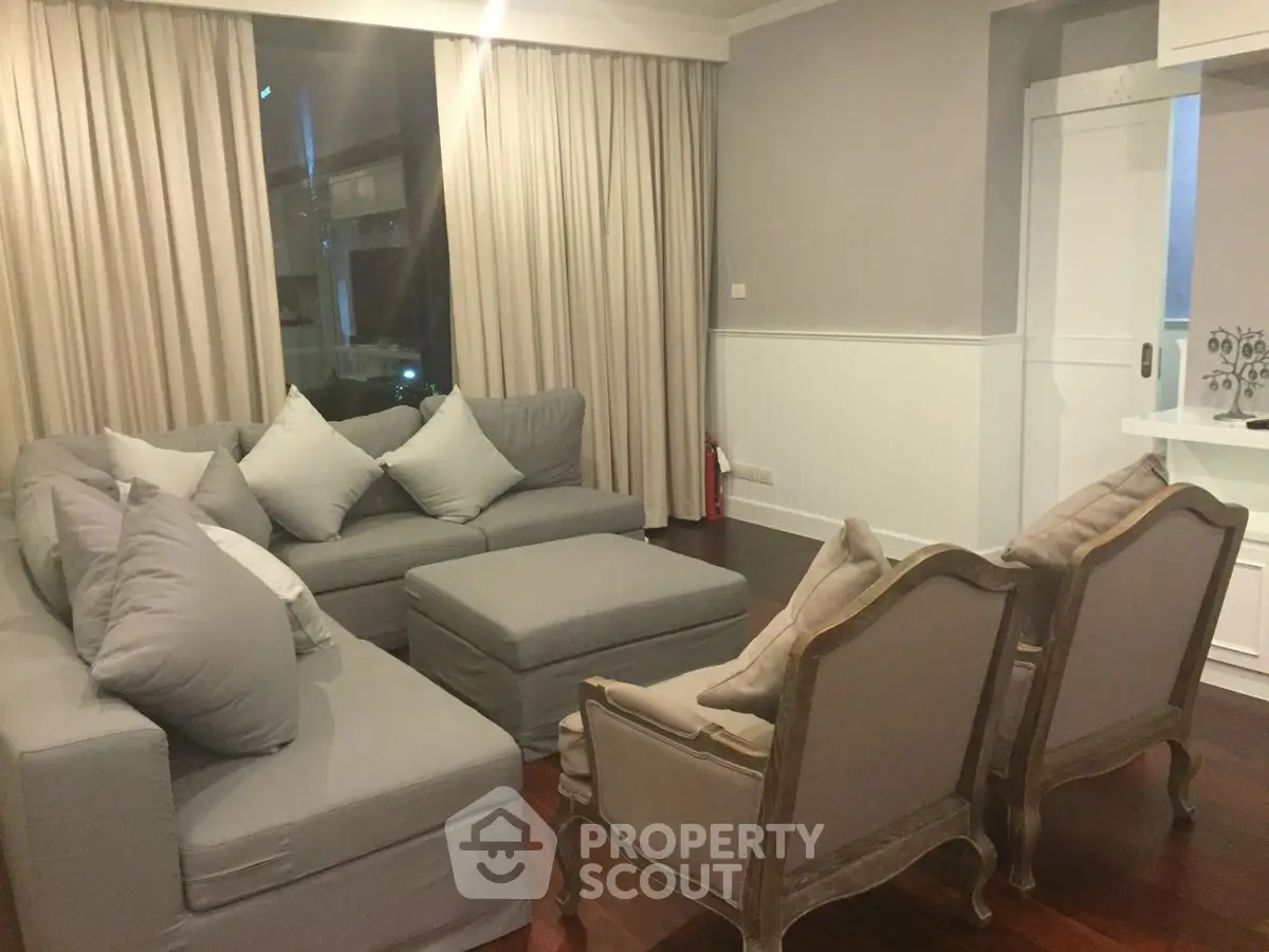 Cozy living room with elegant gray sofa and classic armchairs, perfect for relaxation.