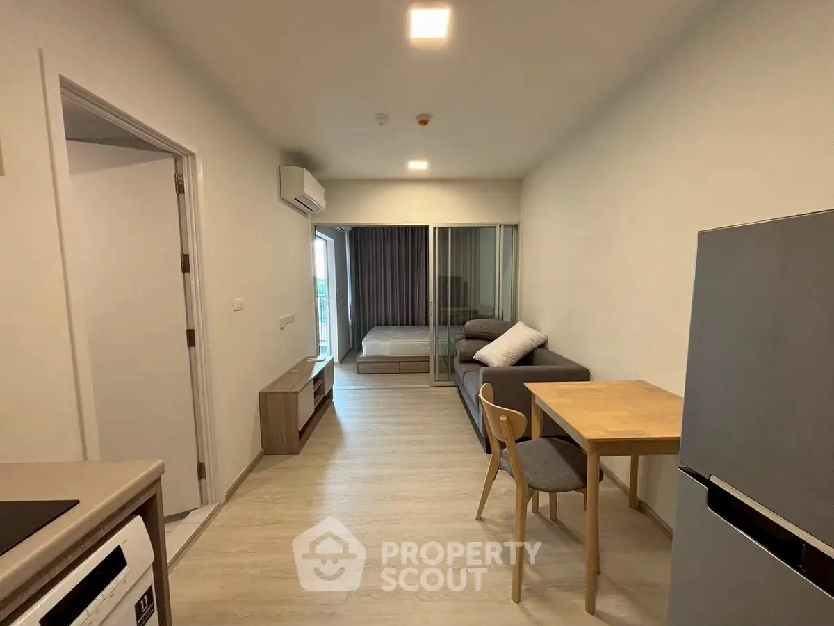 Modern apartment interior with open layout, featuring a cozy living area and compact kitchen.