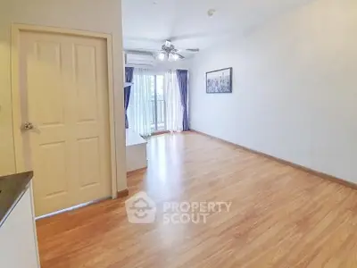 Spacious living room with wooden flooring and balcony access in modern apartment.