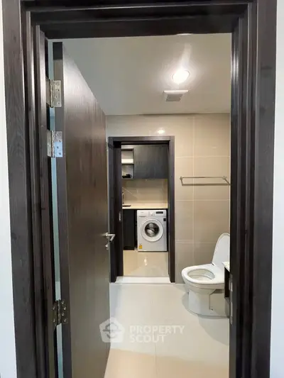 Modern bathroom with washing machine and sleek fixtures in a contemporary apartment.