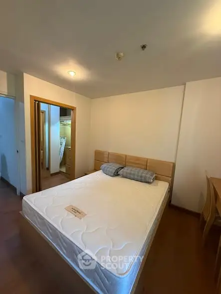 Spacious bedroom with wooden flooring and a comfortable bed in a modern apartment.