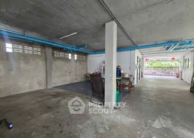 Spacious industrial-style garage with concrete floors and exposed pipes, ideal for storage or workshop use.