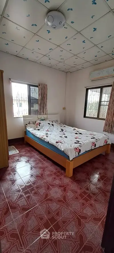Cozy bedroom with patterned ceiling and tiled floor, featuring a comfortable bed and natural light from two windows.