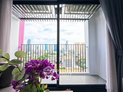 Stunning city view from modern apartment balcony with vibrant purple flowers.