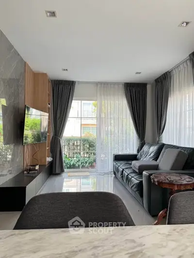 Modern living room with sleek furniture and large windows offering natural light.