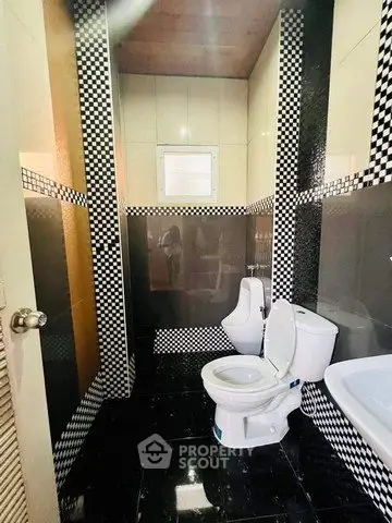 Modern bathroom with stylish black and white checkered tiles and dual toilets.