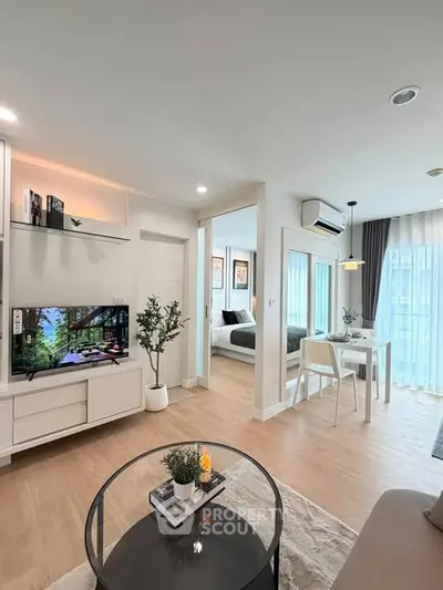 Modern open-plan living room with dining area and bedroom view, featuring stylish decor and natural light.