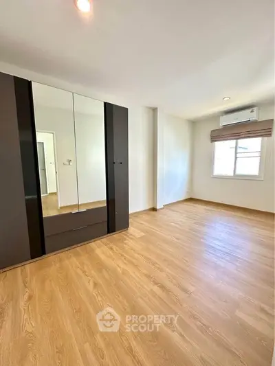 Spacious empty bedroom with wooden flooring and large wardrobe, perfect for customization.