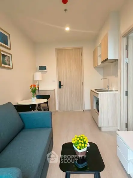 Modern compact living room with kitchenette, stylish decor, and cozy seating area.
