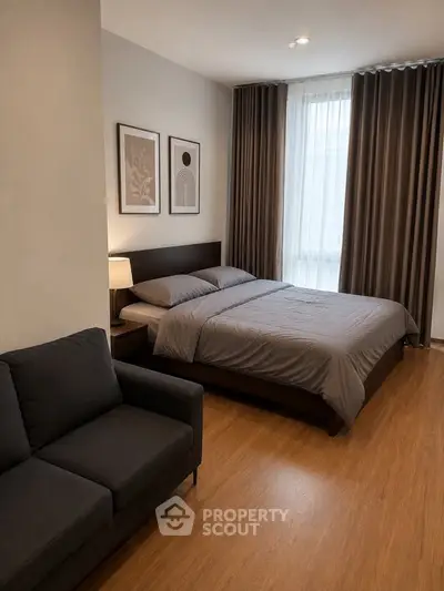 Modern bedroom with cozy decor and natural light, featuring a comfortable bed and stylish sofa.