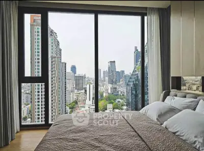 Luxurious bedroom with stunning city view from large window in high-rise apartment.