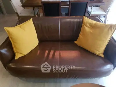 Stylish brown leather sofa with yellow cushions in modern living room setting.