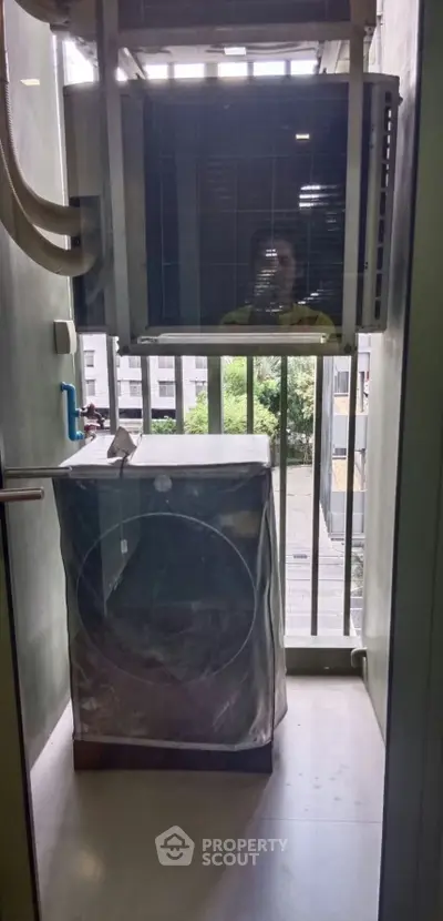 Compact balcony with washing machine and air conditioning unit in urban apartment.