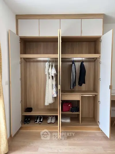 Spacious wooden wardrobe with clothes and accessories in modern bedroom