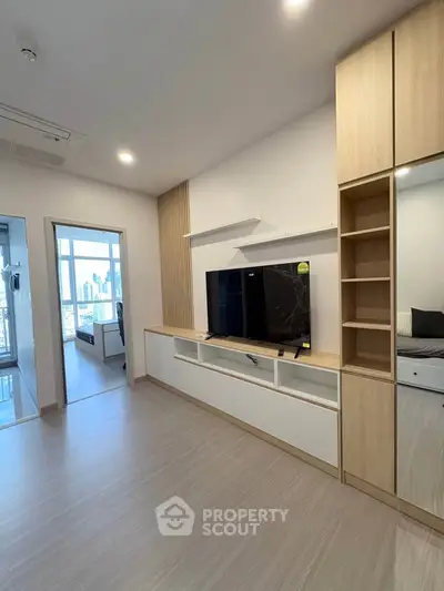 Modern living room with sleek built-in TV unit and city view from adjacent room.