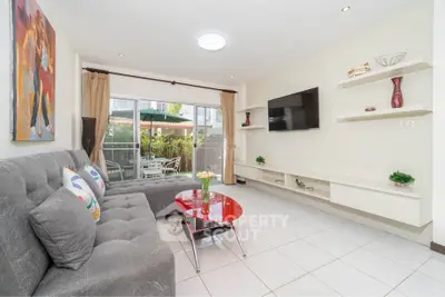 Spacious living room with modern decor and garden view, featuring a large sofa and wall-mounted TV.