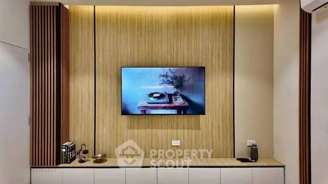 Modern living room with stylish wooden paneling and mounted TV, perfect for cozy entertainment.