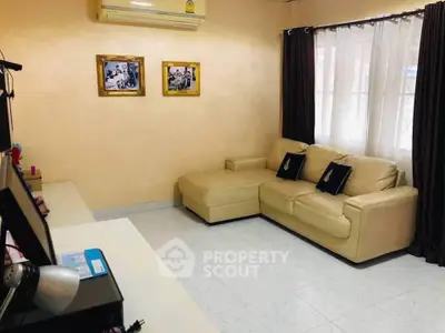 Cozy living room with beige sectional sofa and wall-mounted air conditioner